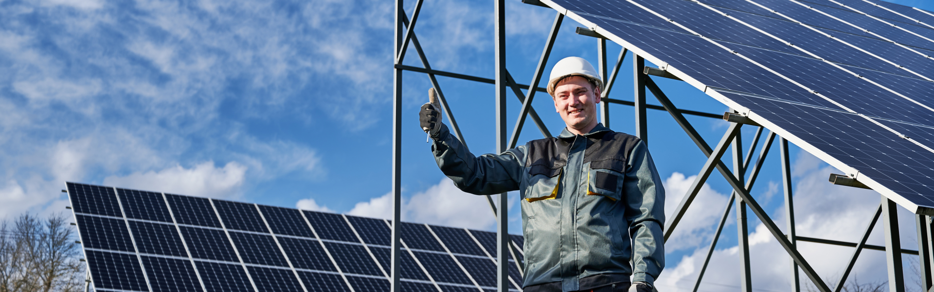 Man technician showing approval gesture thumbs up while standing near solar photovoltaic panel system